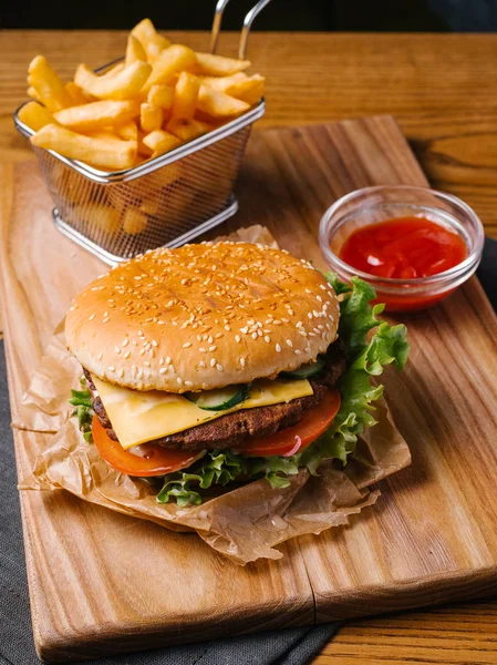 Kızartma sepeti ve tatlı ketçap ile iştah açıcı çizburger üzerinde Ahşap doğrama tahtası hizmet