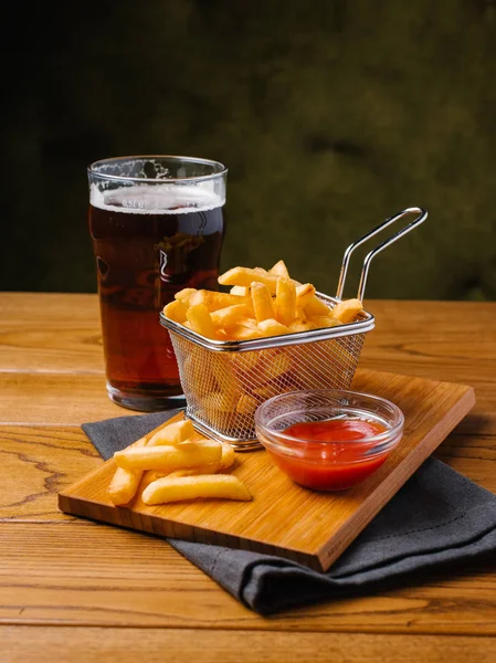 İştah açıcı kızartma sepeti, soğuk bira ve tatlı ketçap gri peçete ile Ahşap doğrama tahtası yılları arasında görev yapmıştır