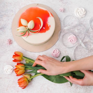 Erkek bileşimi holding lale, beyaz eller ve dekore edilmiş kırmızı pasta, şerit ve meringues