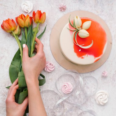 Erkek bileşimi gıda holding kırmızı lale, beyaz eller ve dekore edilmiş kırmızı pasta, meringues ve şerit