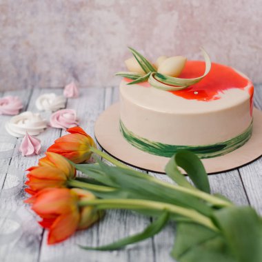 Beyaz ve kırmızı closeup kırmızı lale, meringues ve ahşap plakalar arka plan ile kek dekore edilmiştir.