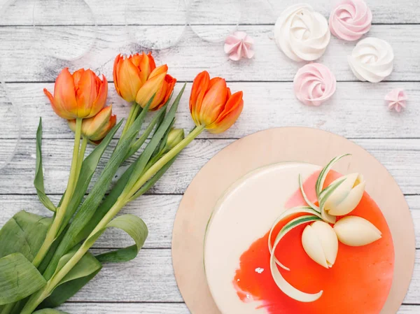红色郁金香和木木板在背景上的白色和红色装饰蛋糕的顶部视图 — 图库照片