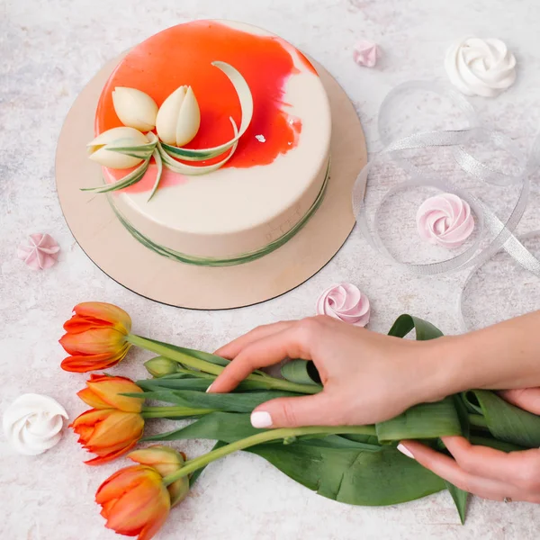 女性手捧郁金香 白色和红色装饰蛋糕 丝带和蛋白甜饼的组成 — 图库照片