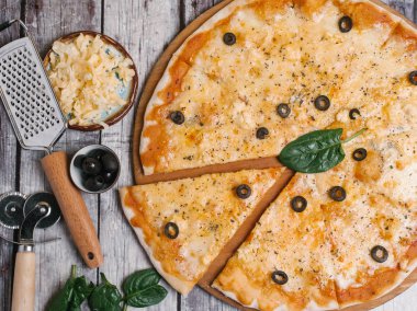 Mozzarella peyniri, parmesan, domates sosu ve zeytin pizza servis ahşap pizza plaka pizza kesici ile eski püskü ahşap plakalar zemin üzerine rende