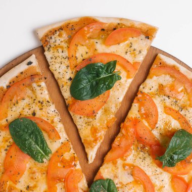 Ahşap pizza tabakta domates sos, mozzarella, parmesan, domates ve ıspanak yaprakları ile pizza görünümünü kapat