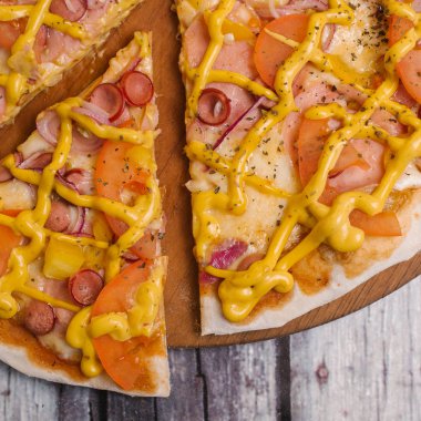 Sarı Görünümü Kapat Pizza domates sosu, hardal sos, mozzarella peyniri, jambon, sosis, domates, biber ve tatlı soğan eski püskü ahşap plakalar arka plan üzerinde ahşap pizza tabakta servis