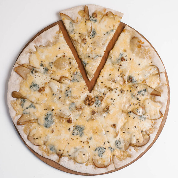Pizza with cream sauce, pears, walnuts, mozzarella and dor blu served on wooden pizza plate