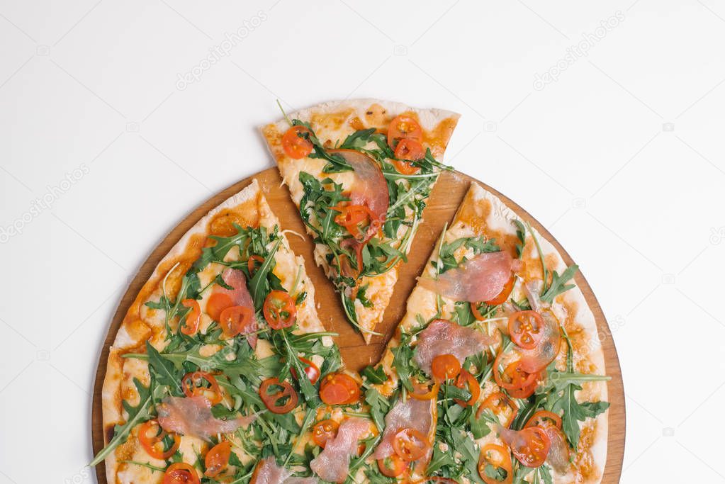 Cropped view of pizza with prosciutto, cherry tomatoes, arugula and mozzarella