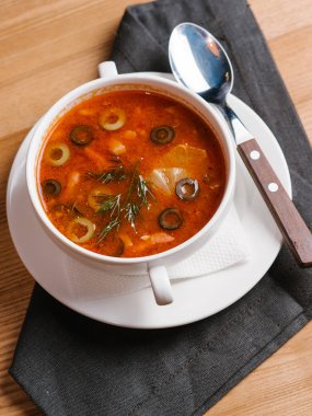 Tabak ve kaşık beyaz kase domates çorbası zeytin, sebze, limon dilimleri ve dereotu ile hizmet