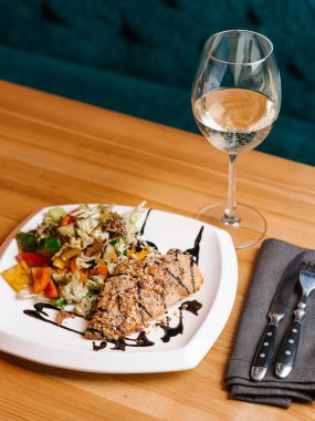 Ekmekli tavuk göğsü ile kıyılmış ceviz ve salata domates, biber, marul ve salatalık balsamik soslu beyaz tabak çatal bıçak takımı, peçete ve beyaz şarap servis