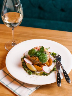 Pişmiş somon ile krem peynir, kızarmış patates dilimleri, turp dilimleri, ıspanak yaprakları ve limon dilim bıçak, çatal ve beyaz şarap ile beyaz tabakta servis