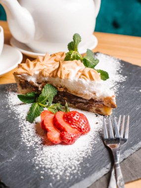 Pasta Bisküvi, meringues ve krem çikolata nane yaprakları ile taş tabakta servis, dilimlenmiş çilek, toz şeker, çatal ve çay seti