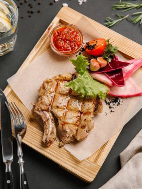 Parşömen kağıtları, limonata, bıçak ve çatal ile ahşap yemek ızgara domuz karnabahar, marul, domates, sarımsak ve Barbekü sos ile servis