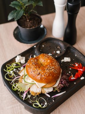Burger tavuk, peynir, salatalık, tatlı soğan ve marul tatlı biber ve dor blu peynir ile ahşap yemek servis