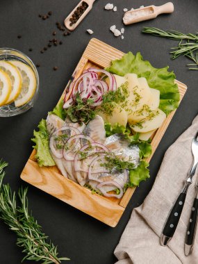 Ringa balığı, tatlı soğan, yeşillik ve marul limonata, çatal ve bıçak ile ahşap yemek üzerine haşlanmış patates hizmet