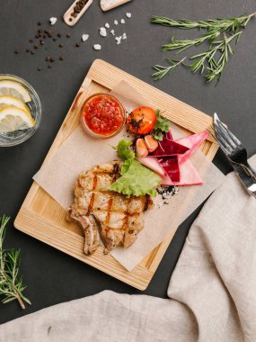 Parşömen kağıt, limonata, bıçak ve çatal ile ahşap yemek gıda kompozisyon ızgara domuz karnabahar, marul, domates, sarımsak ve Barbekü sos ile servis