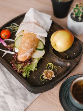 Dilimlenmiş elma, salatalık ve marul vejetaryen baget bütün elma, kiraz domates, tatlı soğan dilimleri ile ahşap yemek servis ve sarımsak pişmiş