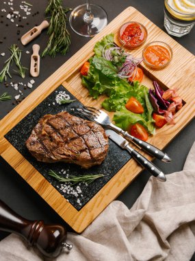 Üstten Görünüm taze domates, marul, tatlı soğan ile ızgara sığır eti biftek ketçap ve barbekü sosu, çatal, bıçak, limonata ve şarap ile ahşap yemek servis