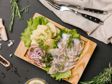 Ringa balığı, tatlı soğan, yeşillik ve marul limonata, çatal ve bıçak ile ahşap yemek üzerine haşlanmış patates hizmet