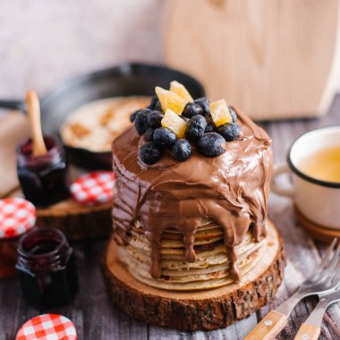 Krep nutella, yaban mersini ve portakal dilimleri ile dekore edilmiş closeup sawed ahşap bardak çay, çatal, reçel ve ahşap masa üzerinde kesme tahtası ile servis