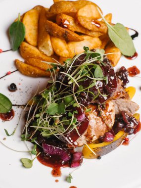 Karamelize tatlı soğan, kabak, berry sos ve bezelye ile kavrulmuş et closeup beyaz tabakta derin kızarmış patates ile lahanası 