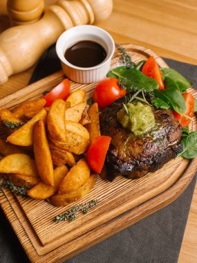 Derin kızarmış patates, taze domates ve soya sosu, biber ve tuz değirmenleri ile Ahşap doğrama tahtası üzerinde hizmet ıspanak ile kavrulmuş et