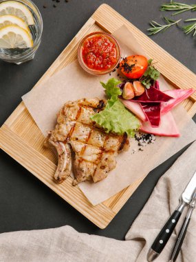 Parşömen kağıtları, limonata, bıçak ve çatal ile ahşap yemek iştah açıcı rilled domuz karnabahar, marul, domates, sarımsak ve Barbekü sos ile servis.