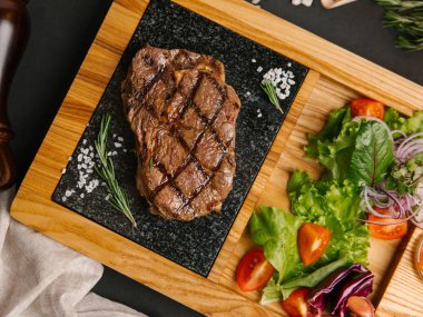 Üstten görünüm taze domates, marul, tatlı soğan ile ızgara sığır eti biftek ahşap tabak üzerinde hizmet 