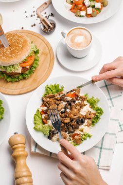 Salatalar, çizburger, kahve fincanı ve çatal bıçak takımı ile erkek el closeup
