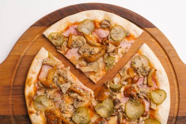 Ahşap pizza tabakta domates sosu, peynir, yabani mantar, jambon ve turşu ile dilimlenmiş pizza Görünümü Kapat 