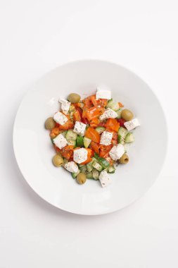Beyaz tabakta zeytin, domates, salatalık, beyaz peynir, zeytinyağı ve baharatlar ile Yunan salatası