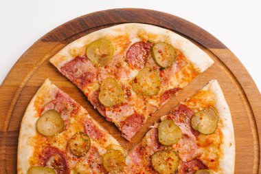 Domates sosu, peynir, sosis, jambon ve ahşap pizza tabakta turşu ile dilimlenmiş pizza Görünümü Kapat 