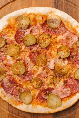 Ahşap pizza tabakta closeup Pizza domates sosu, mozzarella peyniri, sosis, jambon ve turşu ile