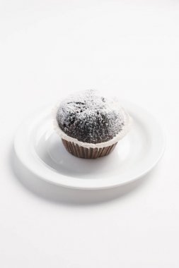 Çikolata muffin beyaz tabakta pudra şekeri ile dekore edilmiş