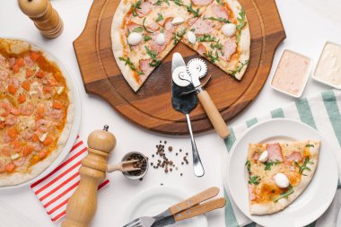Mutfak eşyaları ile beyaz masaya servis pizza çeşitleri
