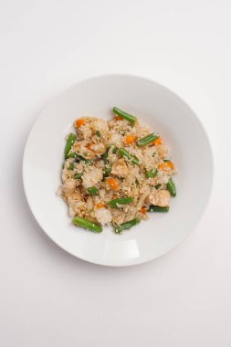 Risotto ile kavrulmuş tavuk parçaları, havuç, lahana ve Fransızca fasulye beyaz tabakta susam ile dekore edilmiş, üstten görünüm