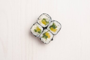 Mango, yosunlar ve Pholadelphia peynir ile maki sushi üstten görünüm bej ahşap yüzeyde hizmet
