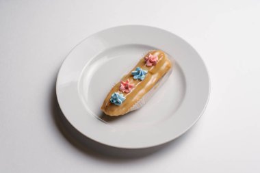 Beyaz kase beyaz arka plan üzerinde izole küçük dekoratif krem çiçekler ile sırlı bej pasta servis