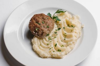 Pirzola ve maydanoz doğrama ile patates püresi closeup izole beyaz arka plan üzerinde beyaz tabakta servis