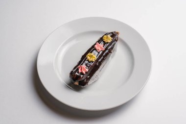 Beyaz kase beyaz arka plan üzerinde izole küçük dekoratif krem çiçekler ile sırlı çikolatalı pasta servis