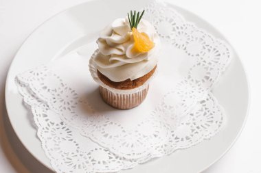 Cupcake tereyağı ile krem ve turuncu hizmet üzerinde beyaz tabak beyaz arka plan üzerinde izole parçası