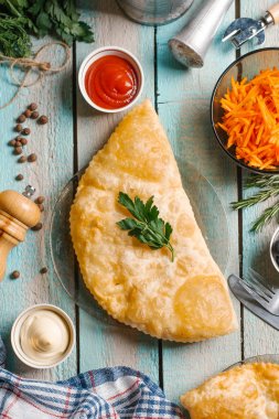 Maydanoz ile süslenmiş chebureks closeup cam tabak mayonez, ketcup, taşlama ve dilimlenmiş havuç ile mavi ahşap masa üzerinde yılları arasında görev yapmıştır