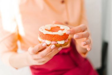 Sünger katmanları, yapılan sanatsal bir şekilde dekore edilmiş tatlı tutan eller closeup çırpılmış krem, dekoratif çiçek ve beyaz çikolata yüzük