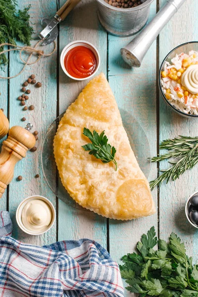 Cheburek closeup cam tabak üzerinde mavi ahşap masa üzerinde mayonez, ketcup, öğütücüler ve salata ile servis maydanoz ile süslenmiş