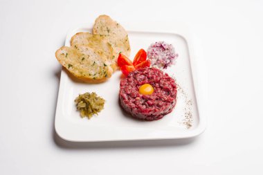 Beyaz tabakta biftek tartare Bıldırcın yumurta, kruton ve dilimlenmiş sebze