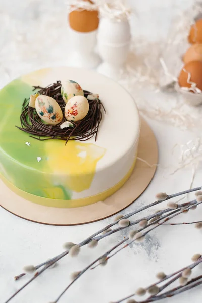 Food composition of glazed cake with eggs, beige napkin, cut paper and willow branches