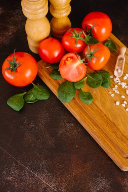 Taze domates, fesleğen, ahşap tahta üzerinde kepçe ile deniz tuzu