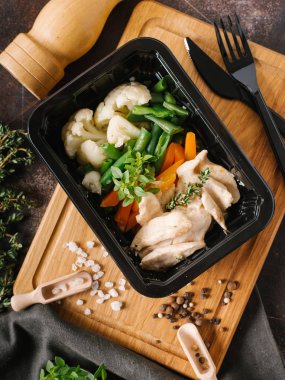 Karnabahar, havuç ve siyah bıçak ve çatal, tuz ve biber ile tabakta kuşkonmaz tavuk.