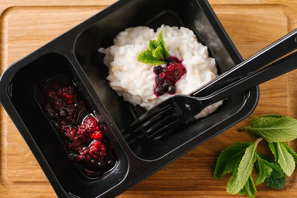 Risotto with wild berries served on black plate with knife and fork