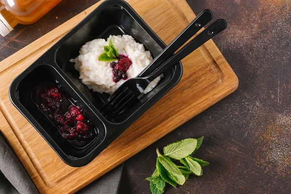 Risotto with wild berries served on black plate with knife and fork